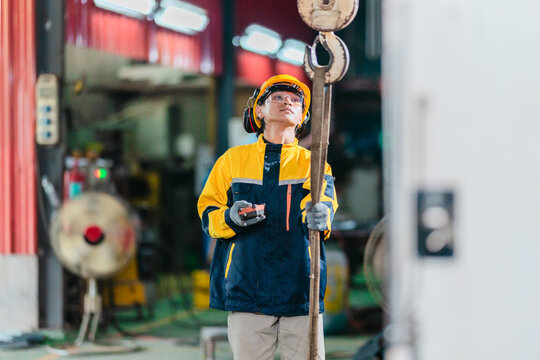 Industrial Technician Controls Overhead Crane in Metal Workshop