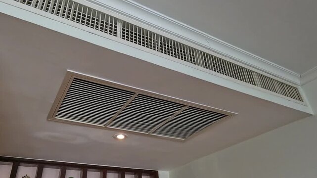 Low angle video of central air conditioning ventilation system on ceiling in modern room indoor.