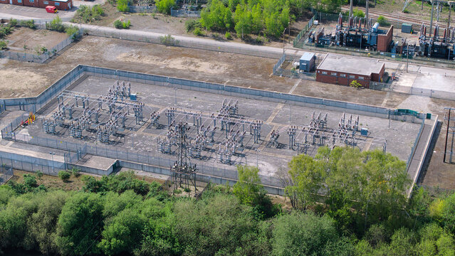 Aerial view of the National Grid Ferrybridge A Substation with electrical infrastructure and transformers surrounded by lush green trees in Knottingley, England, United Kingdom.