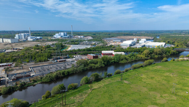 Aerial view of the National Grid Ferrybridge A Substation and industrial complex along the River Aire with green fields and power lines in Knottingley, England, United Kingdom.