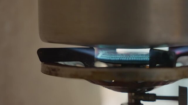 Intense blue flame under pot, high heat cooking moment with rapid boiling and searing energy, professional kitchen vibe with visible grate and valve, orange flame tips and focused closeup detail,