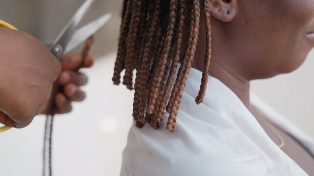 Closeup of braid trimming process. Salon scene focusing on braid trimming with careful scissors work. Closeup of woman getting her braided hair neatly trimmed with focused scissors