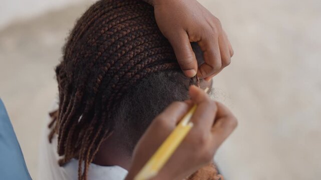Closeup black braider finishing cornrows with precision, comb aligning neat rows, textured ends blended, focused hands, salon atmosphere, symmetry and craft highlighted, cultural artistry