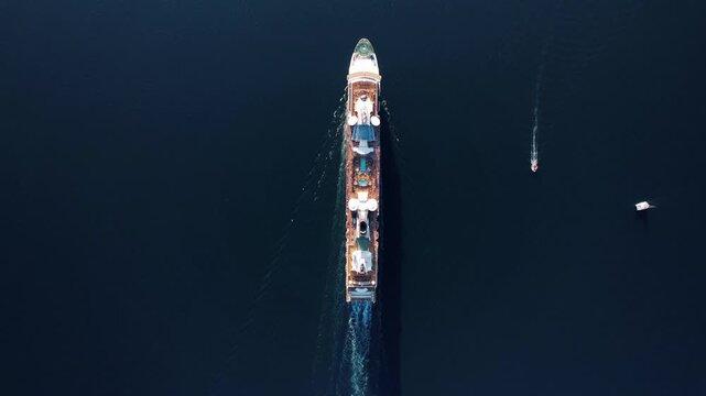 Massive industrial cargo vessel traversing serene blue ocean with escort boats