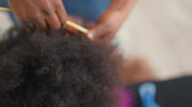 Closeup afro hair detangling with gentle hands, parent caregiver smoothing textured curls, widetooth comb and finger separation, cozy domestic light, patient slow routine for scalp comfort