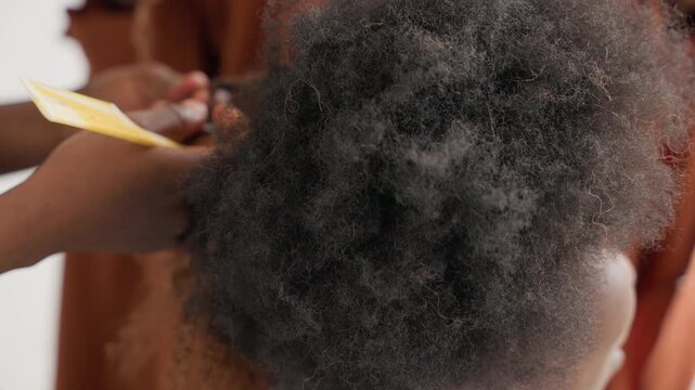 Overhead hands shaping black afro with pick and fingers, creating lift and volume while smoothing edges studio light highlights texture and coil, friendly careful interaction, playful yet attentive