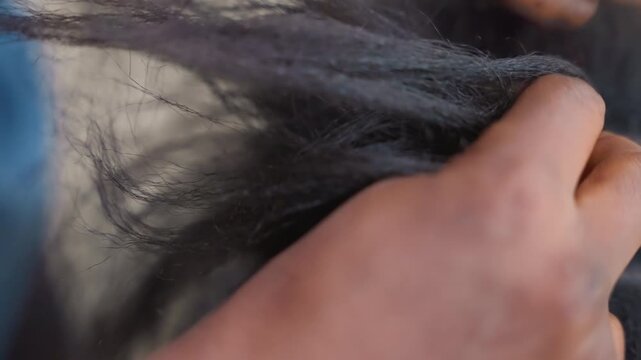 Closeup black apprentice weaving extensions into textured hair, focused fingers adding length and securing strands, busy salon training vibe, practical skill development under natural light