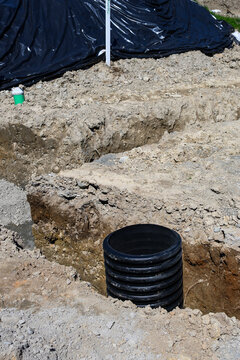 Septic Tank Riser, large black plastic corrugated pipe, installed in trench dug out in dirt of housing development construction project, site preparation detail earthwork
