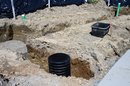 Septic Tank Riser, large black plastic corrugated pipe, installed in trench dug out in dirt of housing development construction project, site preparation detail earthwork
