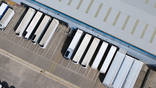 Aerial view of white semi-trailers parked at loading bays of a large industrial warehouse in Doncaster, England, United Kingdom.