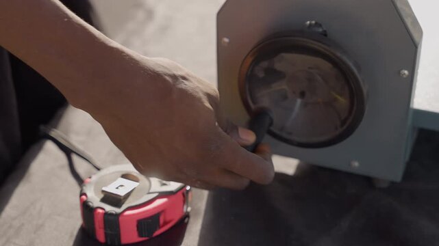 Closeup black carpenter adjusting disc sander. Dusty hands turning knob near tape measure, close focus on sander housing and motor, tactile grit on skin, sunlight highlights metal and finish, careful