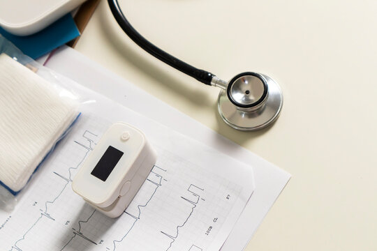 On the doctor's desk, there is a stethoscope and an oxygen monitor for checking the patients' health.
