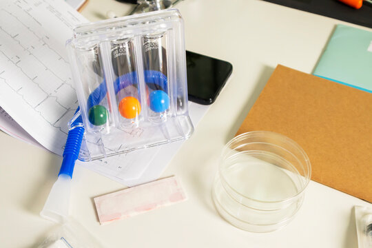 Three-ball Incentive Spirometer for lung breathing exercise on a medical desk.