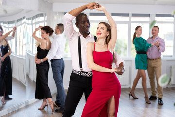 Fototapeta premium Happy man and woman in elegant clothes performing ballroom dance in dancing room during celebration or party