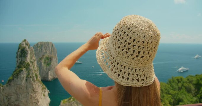 A woman looking at the sea in Capri forming a heart gesture with her hands toward the scenery