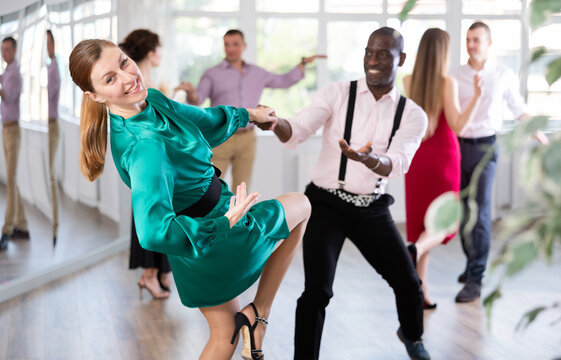 Positive woman and man dancing foxtrot in pair during group dance party