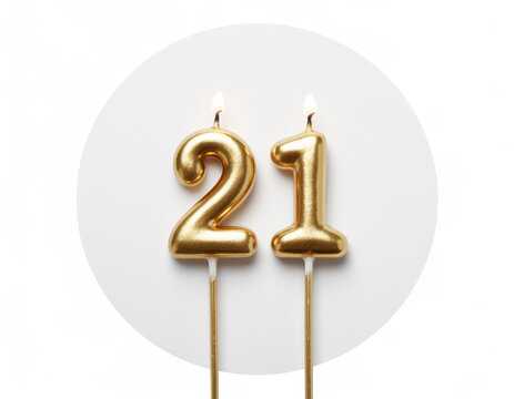 Two gold birthday candles shaped as the number twenty-one with lit flames on white background