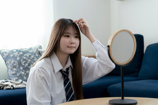 鏡を見ながら髪を整える日本人女子高生