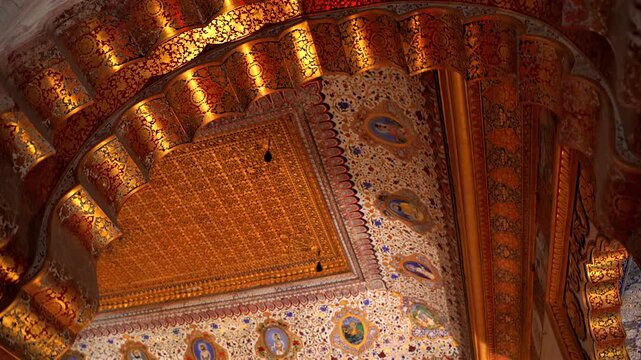 A close-up static shot looking up at the magnificent gold-leaf ceiling and intricately painted arched details of the Phool Mahal interior in Mehrangarh Fort, Jodhpur, Rajasthan, India