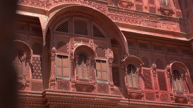A close-up static shot of the exquisite stone lattice work and ornamental arches on the facade of Mehrangarh Fort, showcasing traditional Rajput craftsmanship in Jodhpur, Rajasthan, India