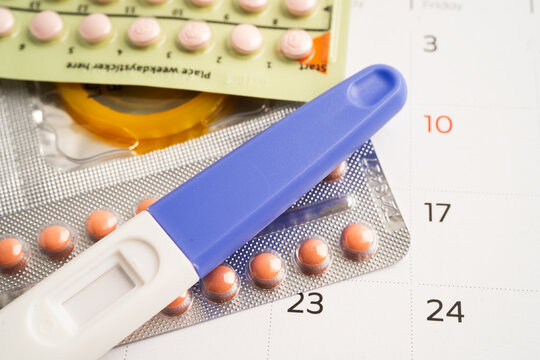 Pregnancy test and birth control pills on calendar, contraception health and medicine.