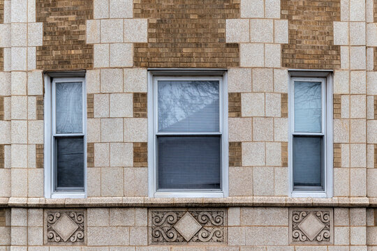 Three rectangular windows on a brick wall clad in beige tiles, with bas-reliefs beneath the windows. From the Windows of the world series.