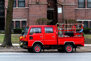 Fototapeta premium Small red truck was parked on one of the streets in Chicago, across from a red-brick house.