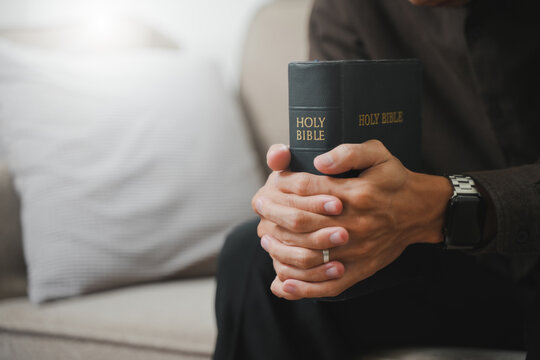 Christians and Prayer  A group of Christians hold hands in prayer and worship to demonstrate their faith, with a Bible placed on a wooden table for prayer.
