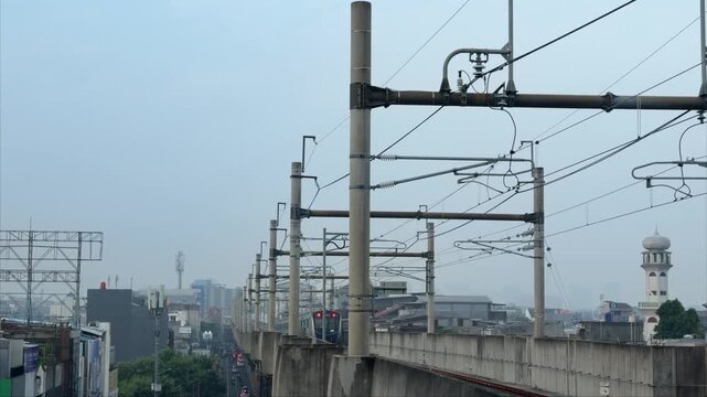 Modern MRT train traveling on an elevated railway in Jakarta, Indonesia with urban buildings and city skyline in the background. Infrastructure and public transportation system in a metropolitan area 