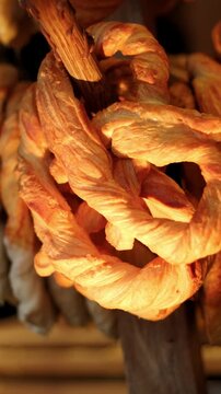 Golden baked pretzel hanging on display. Fresh pastry snack close up in bakery. Tasty knotted dough product for traditional breakfast or food celebration concept.