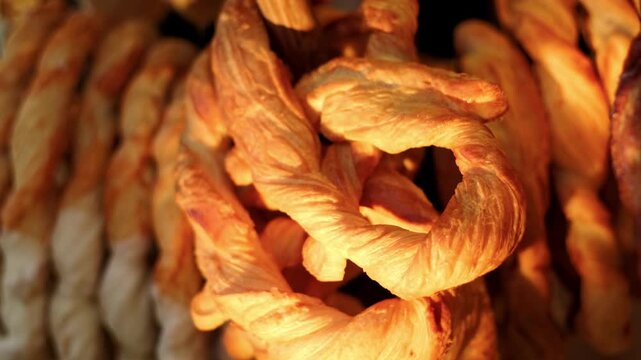 Golden baked pretzel hanging on display. Fresh pastry snack close up in bakery. Tasty knotted dough product for traditional breakfast or food celebration concept.