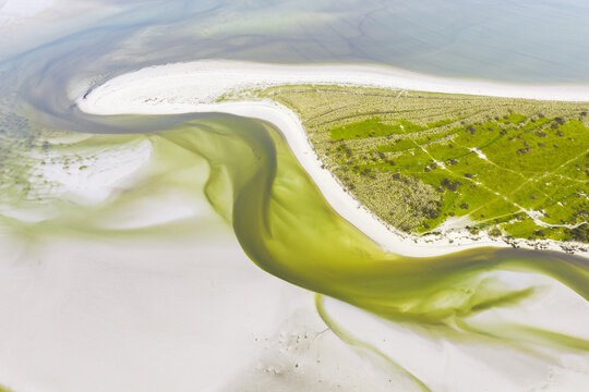 Aerial view of the winding water channels and white sandbanks of the coastal landscape in Goulven, Brittany, France.
