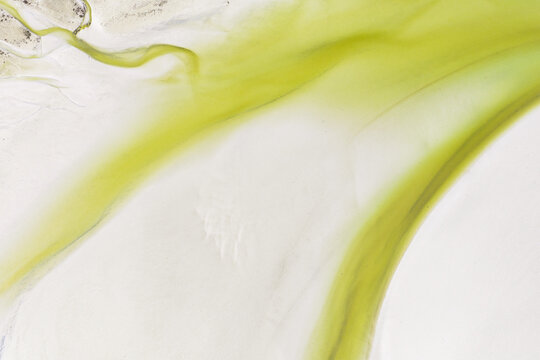 Aerial view of abstract patterns of green algae flowing across white sand flats at low tide in Goulven, Brittany, France.