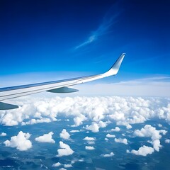 Obraz premium Airplane wing above fluffy clouds and blue sky