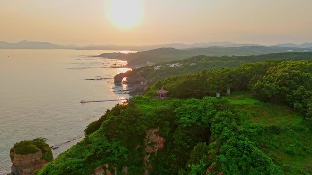 Cinematic shot of a traditional Chinese pagoda perched atop dramatic coastal cliffs, golden light, sweeping ocean views. Perfect for travel, culture, and documentary productions.