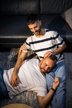 A relaxed gay couple sharing an affectionate moment while resting together on a sofa at home.