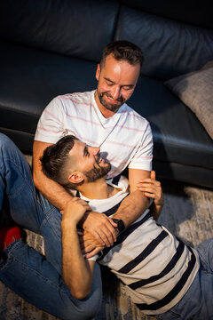 A loving same sex male couple enjoying a peaceful moment of connection on a sofa at home.
