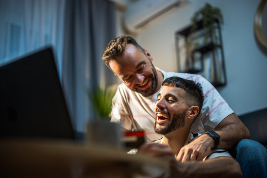 A young same sex couple planning a purchase and paying online with a credit card at home.