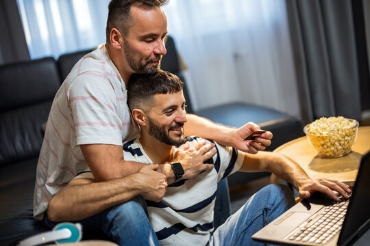 A relaxed same sex couple enjoying a seamless online shopping experience with a laptop and credit card.