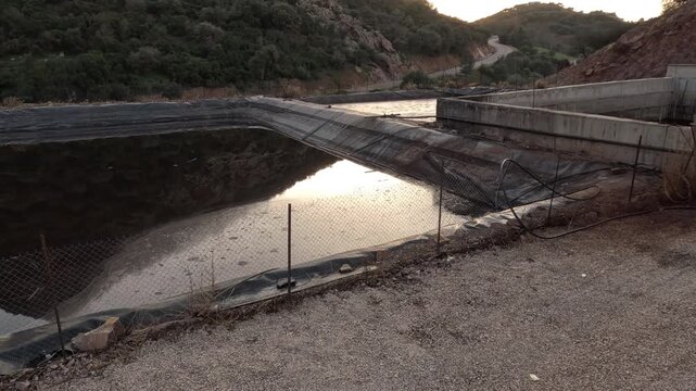 Olive mill basin storing pomace and wastewater from extraction process. Dark effluent with organic residues collected in lined pond, highlighting environmental management and waste handling in oil pro
