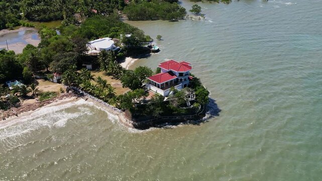 Aerial orbit of a seaside heritage mansion with palm-lined grounds and surrounding ocean waters at Roca Encantada, Guimaras, Philippines.