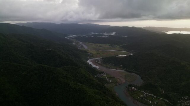 Stunning aerial overview of a winding river flowing through lush mountains and rural terrain in Sibacungan, Bato, Catanduanes, Philippines.