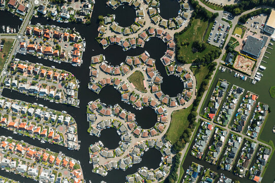 Aerial view of unique circular residential clusters built on water with private boat docks and lush green lawns in a modern waterfront development Lemmer, Friesland, Netherlands.