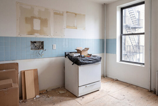 Empty kitchen undergoing renovation with exposed wires and old stove