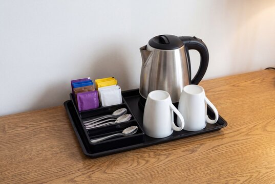 Electric kettle with mugs and tea bags on a wooden table