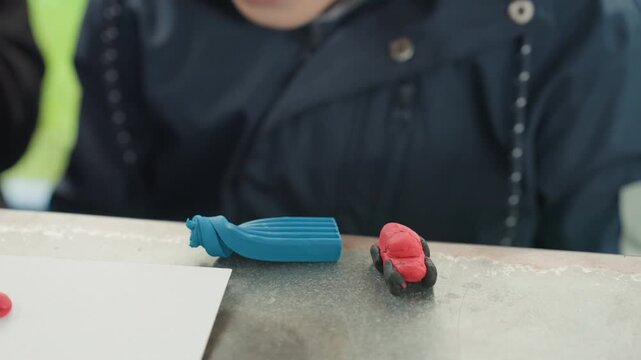 Child at desk with erasers preparing back to school supplies, closeup of small student arranging blue pencil case and red eraser on tabletop, candid outdoor light, focused hands, textured surface,