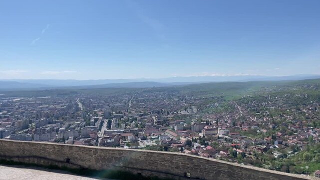 Wide-angle panoramic panning shot of Deva, Romania, taken from the historic Deva Citadel, showing the urban landscape, residential areas, and the surrounding green plai
