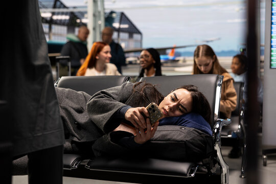 Worried woman using phone in airport, seeing delays in plane departure online timetable. Tourist using smartphone troubled by travel itinerary being affected by cancelations during flight layover