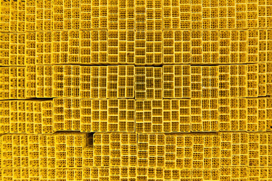 Aerial view of stacked yellow plastic crates creating a repetitive geometric pattern in an industrial storage area.
