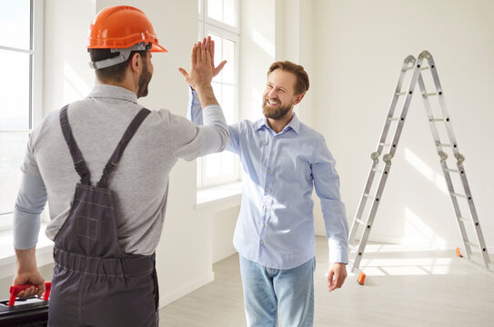 Happy client exchanges high five with foreman or worker amid home renovation, marking success, infusing the project space with professional joy and a sense of accomplishment in a domestic setting.